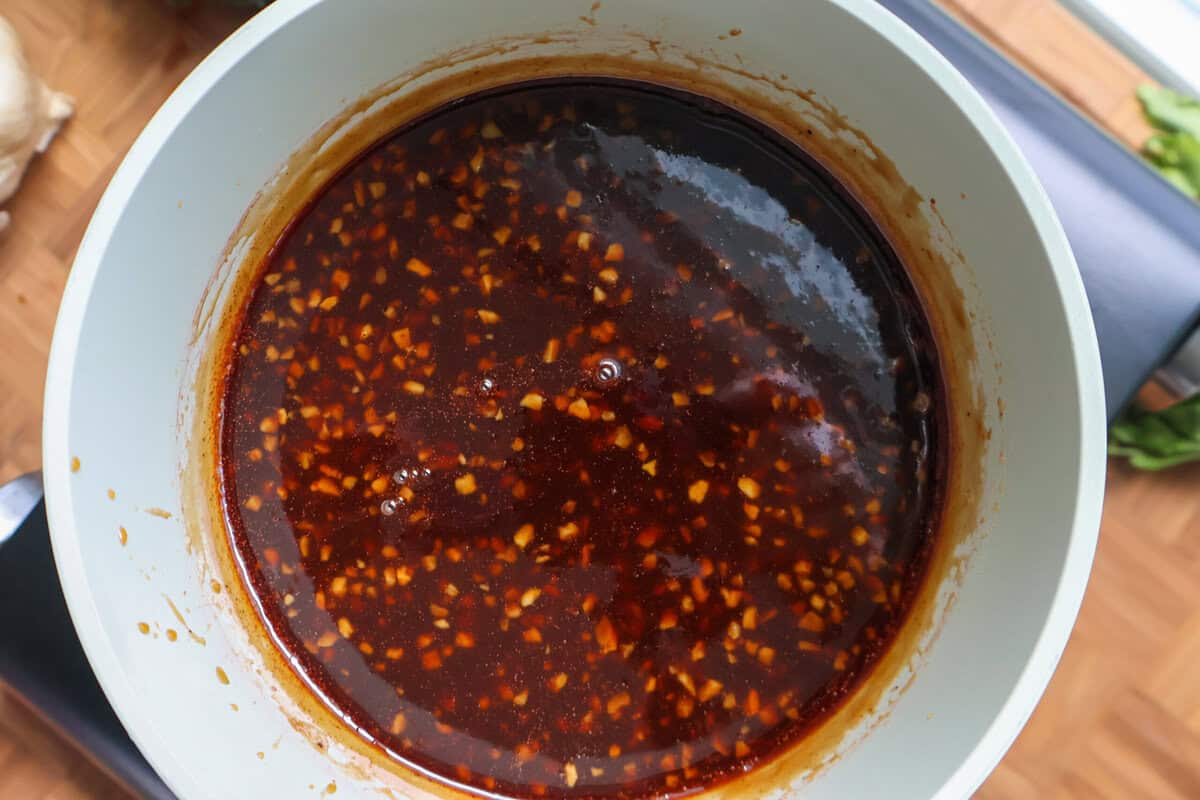 Glossy BBQ glaze simmering in a saucepan after the grape jelly has melted in