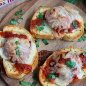 Texas toast meatball melts topped with melted mozzarella on a cutting board