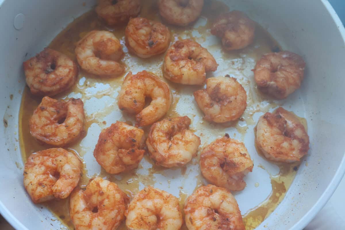 Blackened jumbo shrimp cooking in a skillet for surf and turf pasta