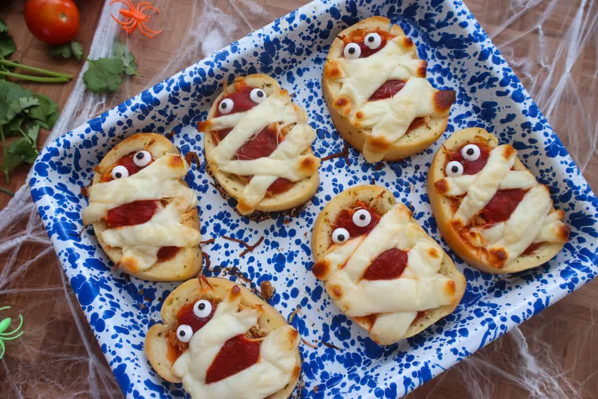Chicken parmesan mummy garlic bread on a blue speckled tray for Halloween