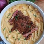 Creamy surf and turf pasta with sliced blackened ribeye steak and shrimp in a skillet
