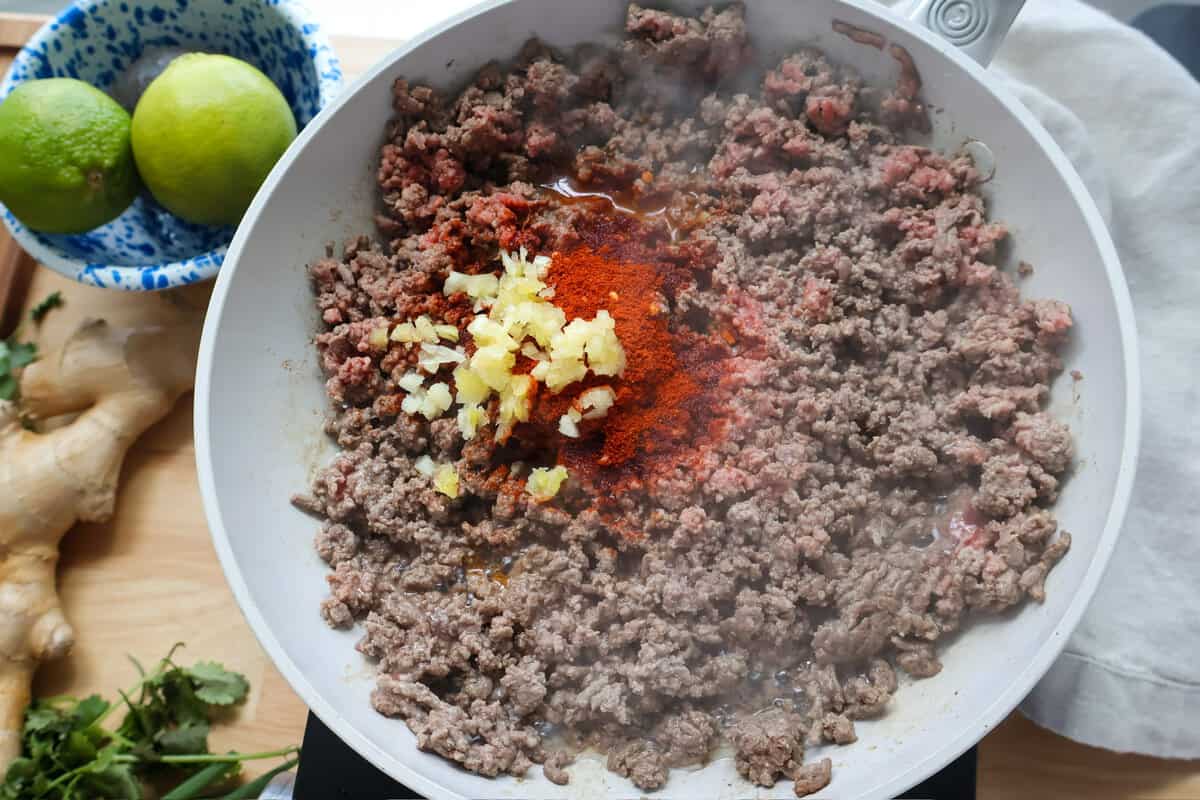 Smoked paprika, minced garlic, and spices added to ground beef browning in a skillet