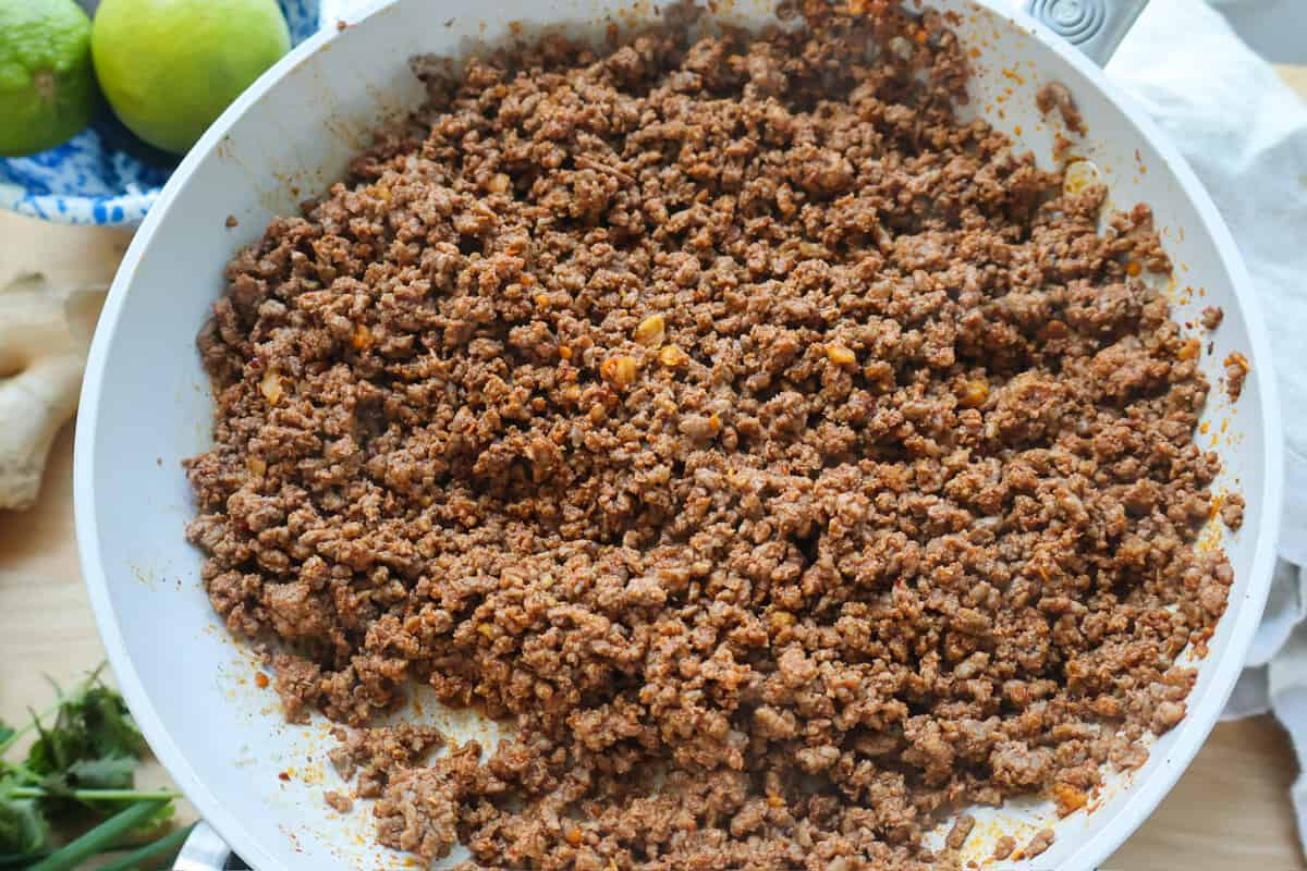Crispy browned seasoned ground beef in a white skillet