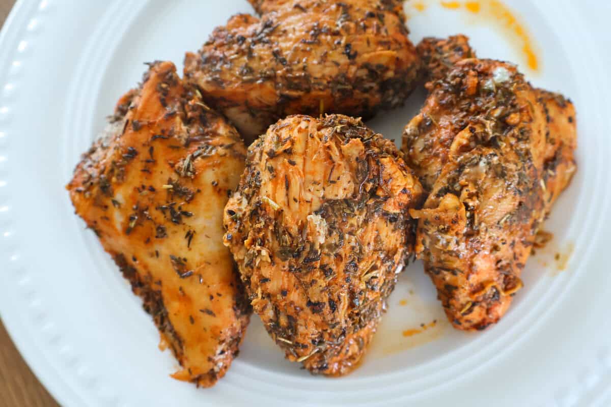 Cooked seasoned chicken breasts resting on a plate.