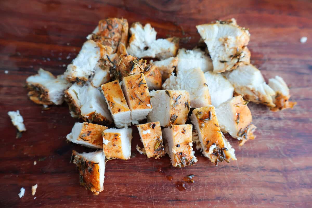 Diced seasoned chicken breast on a cutting board.