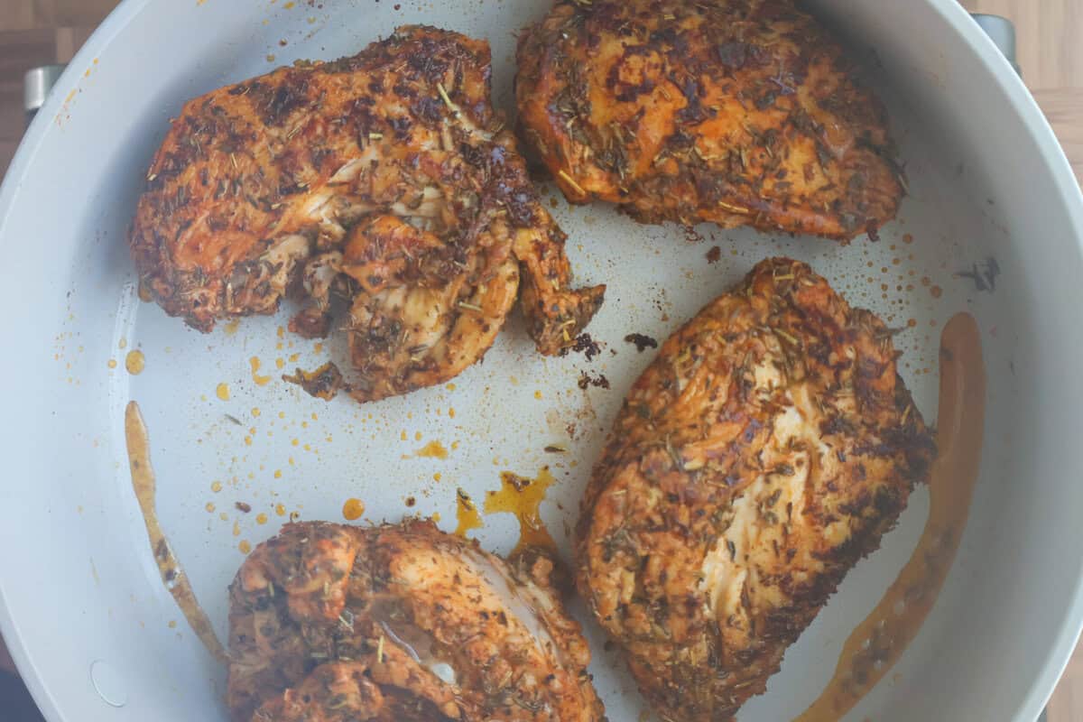 Golden, fully cooked seasoned chicken breasts in a skillet.