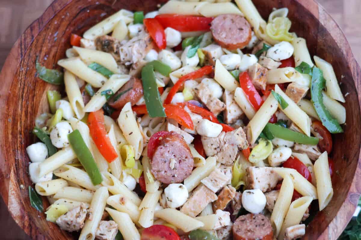 Gluten-free pasta salad tossed with Italian dressing in a large bowl.