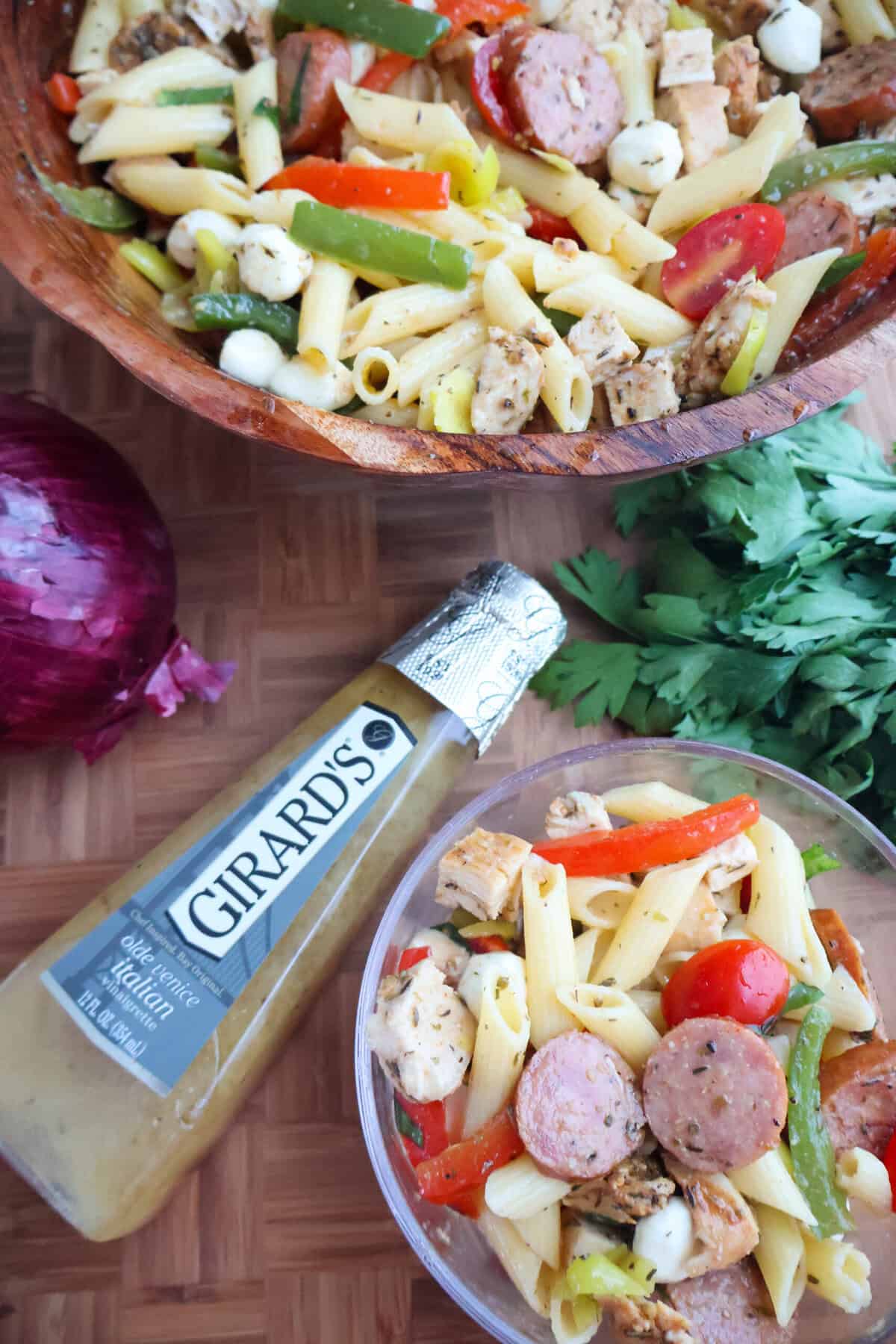 Easy gluten-free pasta salad with Italian dressing, chicken, kielbasa, and mozzarella pearls in a wooden bowl.