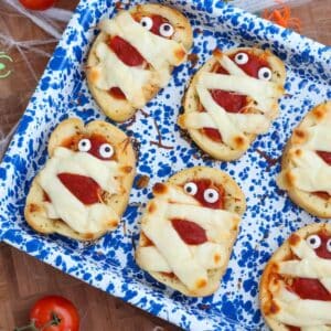 Chicken parmesan mummy garlic bread with googly eyes on a blue speckled baking tray