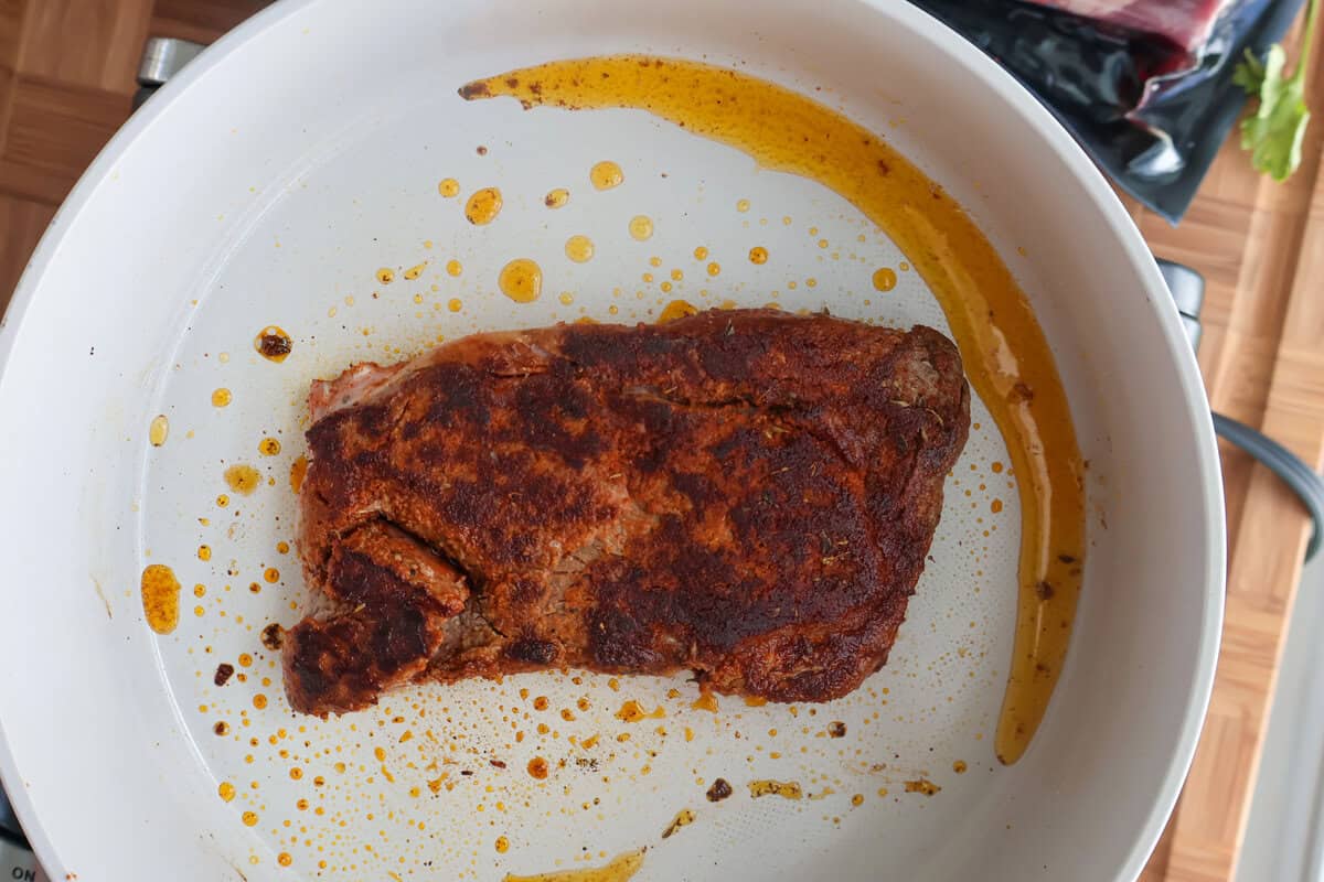 Ribeye steak searing in a skillet with olive oil for surf and turf pasta