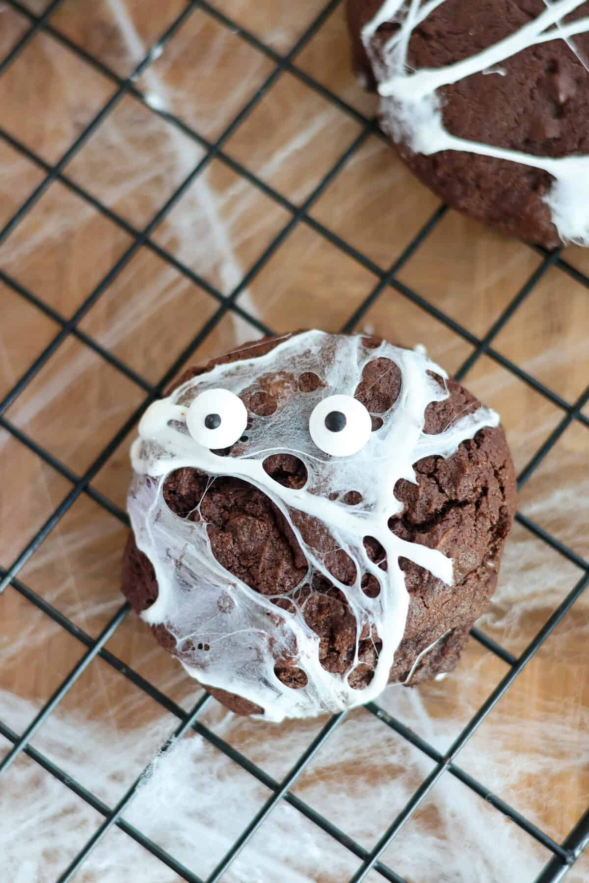 Close-up of a gluten-free spider web cookie with marshmallow webs and googly eyes