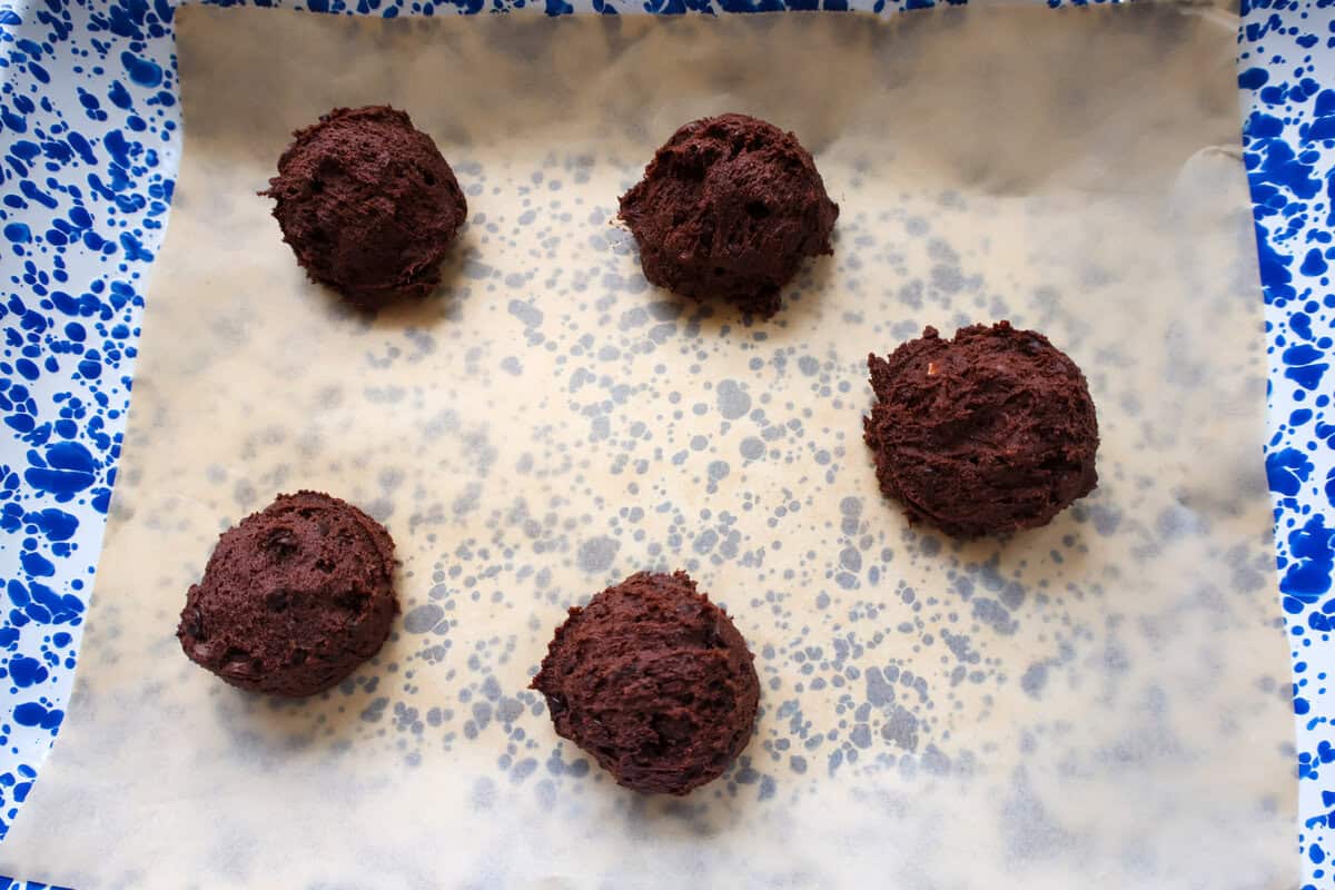 Scooped chocolate cookie dough balls on a parchment-lined baking sheet