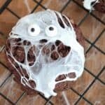 Spider web cookie with marshmallow webs and candy googly eyes on a wire cooling rack