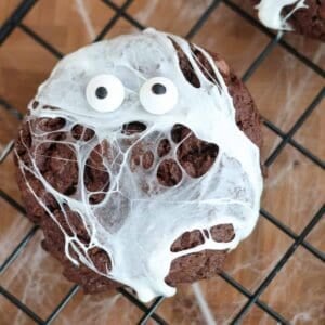 Spider web cookie with marshmallow webs and candy googly eyes on a wire cooling rack
